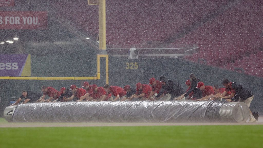 Members of the grounds crew roll the tarp onto the field during a rain delay in the seventh inning ...