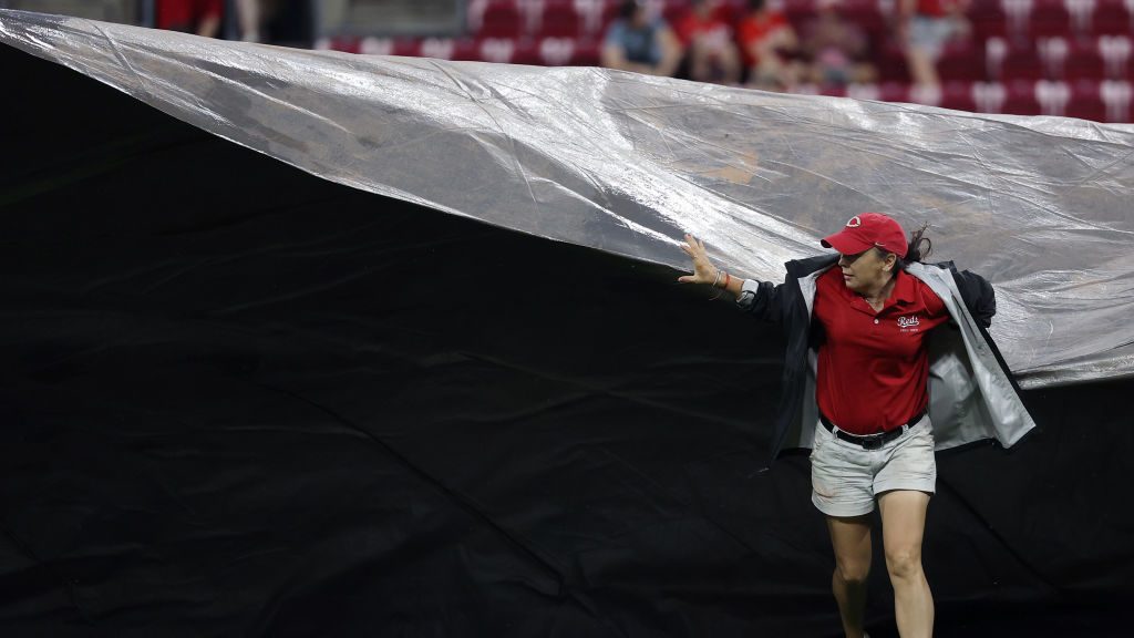 A member of the grounds crew pulls the tarp across the field during a rain delay in the seventh inn...