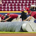 The Cincinnati Reds' grounds crew unrolls a tarp during a rain delay in the eighth inning of the team's baseball game against the Arizona Diamondbacks on Tuesday, June 7, 2022, in Cincinnati. (AP Photo/Jeff Dean)