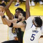 Boston Celtics forward Jayson Tatum, middle, shoots against Golden State Warriors forward Andrew Wiggins, rear, and center Kevon Looney (5) during the second half of Game 5 of basketball's NBA Finals in San Francisco, Monday, June 13, 2022. (AP Photo/John Hefti)