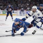 Colorado Avalanche center Nathan MacKinnon (29) falls in front of Tampa Bay Lightning defenseman Erik Cernak (81) during the second period of Game 1 of the NHL hockey Stanley Cup Final on Wednesday, June 15, 2022, in Denver. (AP Photo/John Locher )