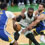 Boston Celtics guard Jaylen Brown (7) drives against Golden State Warriors guard Stephen Curry (30) and center Kevon Looney (5) during the first quarter of Game 6 of basketball's NBA Finals, Thursday, June 16, 2022, in Boston. (AP Photo/Steven Senne)