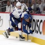 Colorado Avalanche defenseman Bowen Byram (4) is pressed against the boards by Tampa Bay Lightning center Steven Stamkos (91) during the first period of Game 1 of the NHL hockey Stanley Cup Final on Wednesday, June 15, 2022, in Denver. (AP Photo/John Locher )