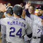 Colorado Rockies' Ryan McMahon is greeted by teammates after scoring against the Arizona Diamondbacks during the seventh inning of a baseball game, Sunday July 10, 2022, in Phoenix. (AP Photo/Darryl Webb)