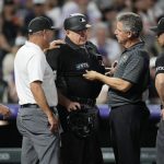 Trainers check on home plate umpire Jerry Layne before he left his position during the sixth inning of a baseball game between the Arizona Diamondbacks and the Colorado Rockies on Saturday, July 2, 2022, in Denver. (AP Photo/David Zalubowski)