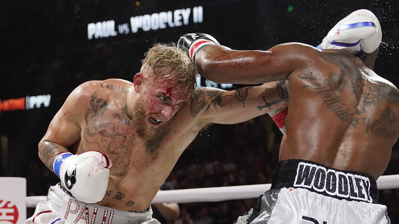 Jake Paul, left, hits Tyron Woodley with a punch during the third round of a cruiserweight boxing b...