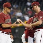 Arizona Diamondbacks starting pitcher Tyler Gilbert, right, hands the ball to manager Torey Lovullo during the sixth inning of a baseball game against the Colorado Rockies, Sunday, July 10, 2022, in Phoenix. (AP Photo/Darryl Webb)