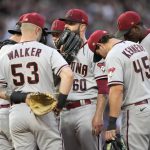 Arizona Diamondbacks starting pitcher Dallas Keuchel, center, confers with teammates after giving up back-to-back walks to load the bases during the fourth inning of a baseball game against the Colorado Rockies on Saturday, July 2, 2022, in Denver. (AP Photo/David Zalubowski)