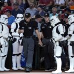 Umpires Andy Fletcher, left, and Junior Valentine are flanked by "Star Wars" stormtroopers as they walk on the field during Star Wars night, prior to a baseball game between the Arizona Diamondbacks and the Washington Nationals on Saturday, July 23, 2022, in Phoenix. (AP Photo/Ross D. Franklin)