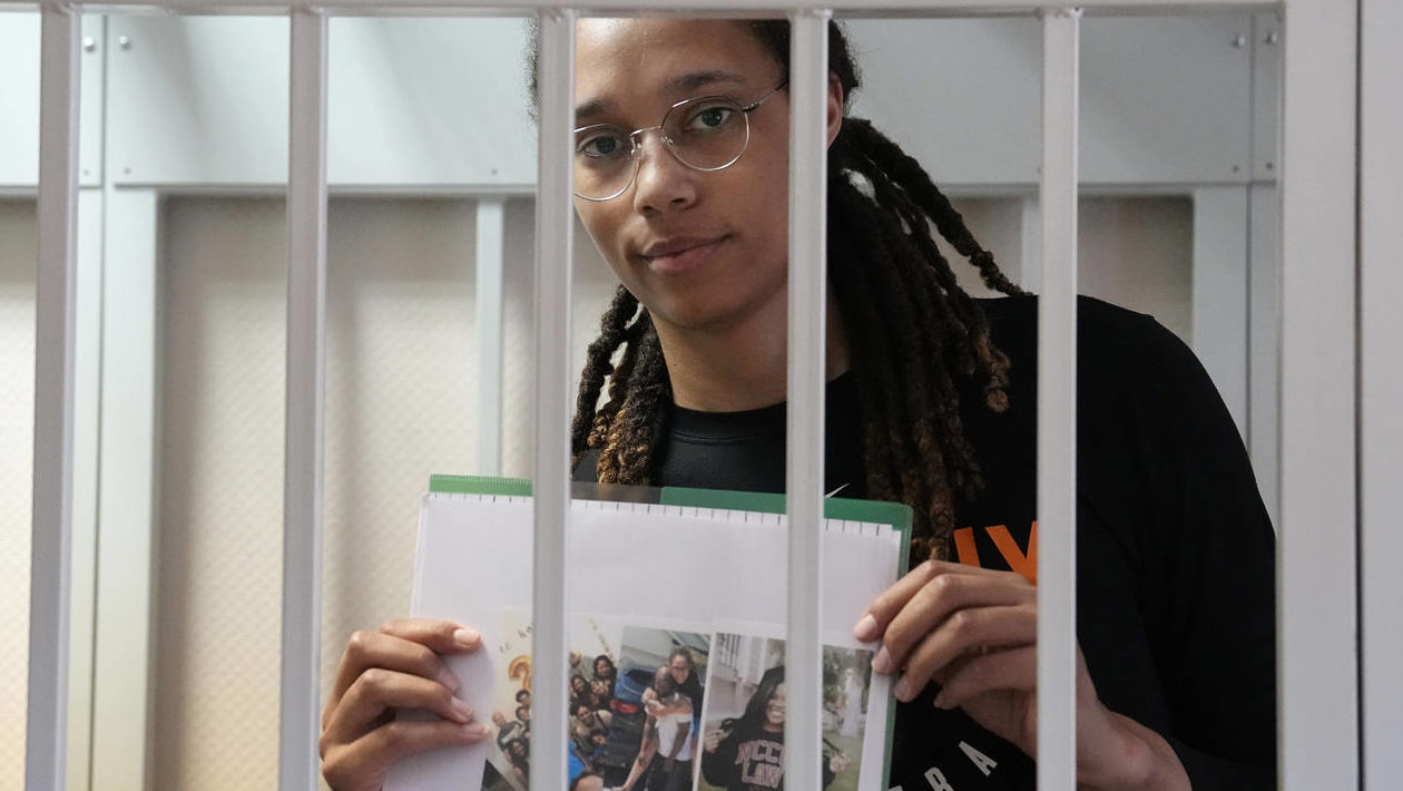 WNBA star and two-time Olympic gold medalist Brittney Griner holds images standing in a cage at a c...