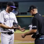Umpire Brock Ballou, right, inspects the hands of Colorado Rockies starting pitcher Austin Gomber during the fourth inning of the team's baseball game against the Arizona Diamondbacks on Thursday, July 7, 2022, in Phoenix. (AP Photo/Ross D. Franklin)
