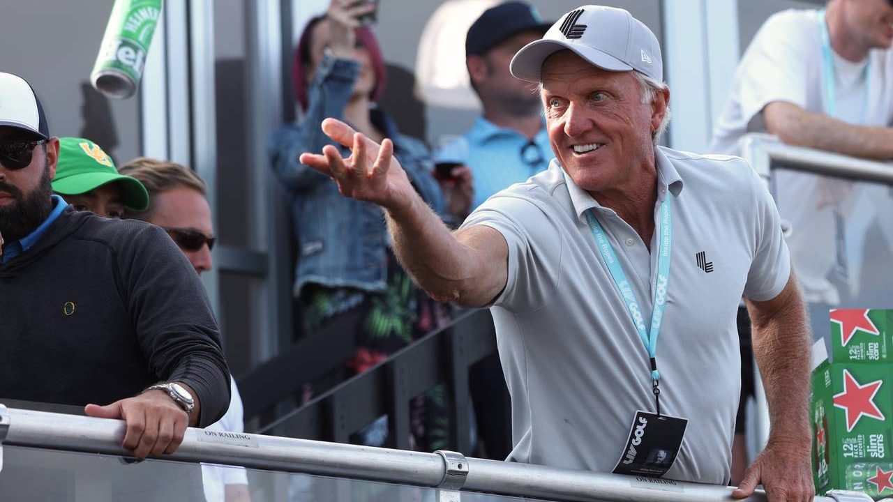 Greg Norman, CEO of LIV Golf, tosses a beer to spectators into the crowd surrounding the 18th green...