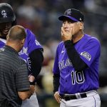 Colorado Rockies manager Bud Black (10) watches a member of the team's medical staff looks at the left wrist of C.J. Cron, left, after Cron was hit by a pitch during the fifth inning of the team's baseball game against the Arizona Diamondbacks on Friday, July 8, 2022, in Phoenix. (AP Photo/Ross D. Franklin)