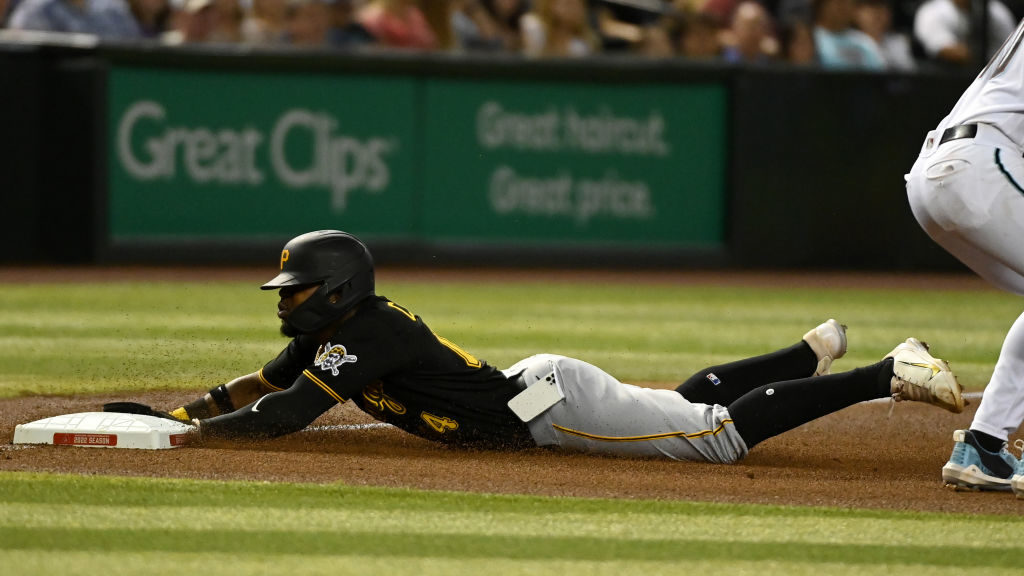 Rodolfo Castro #14 of the Pittsburgh Pirates slides into third base as his cell phone falls out of ...