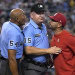 St. Louis Cardinals manager Oliver Marmol, right, is restrained by MLB umpire Jeff Nelson (45) while talking to CB Bucknor (54) in the third inning during a baseball game against the Arizona Diamondbacks, Sunday, Aug. 21, 2022, in Phoenix. Marmol was ejected from the game. (AP Photo/Rick Scuteri)