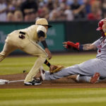 St. Louis Cardinals catcher Yadier Molina, right, is tagged out by Arizona Diamondbacks' Sergio Alcantara while advancing to third on a base hit by teammate Dylan Carlson during the fifth inning of a baseball game, Friday, Aug. 19, 2022, in Phoenix. (AP Photo/Matt York)