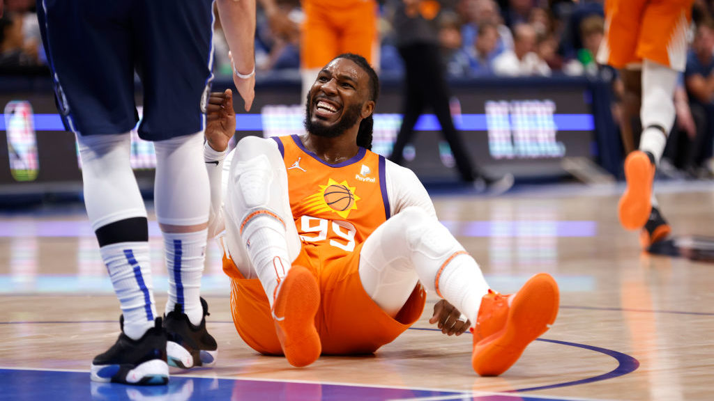 Jae Crowder #99 of the Phoenix Suns is helped to his feet by Luka Doncic #77 of the Dallas Maverick...