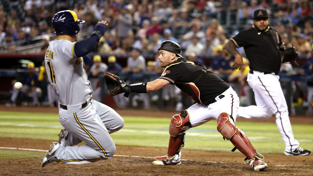 Jace Peterson #14 of the Milwaukee Brewers safely slides into home plate to score a run past catche...
