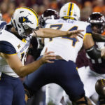 West Virginia quarterback JT Daniels (18) loses control of the ball during the first half of the team's NCAA college football game against Virginia Tech on hursday, Sept. 22, 2022, in Blacksburg, Va. (AP Photo/Steve Helber)