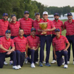 USA team captain Davis Love III, white hat, and his team pose for a photo with the Presidents Cup trophy after defeating the International team in match play at the Presidents Cup golf tournament at the Quail Hollow Club, Sunday, Sept. 25, 2022, in Charlotte, N.C.(AP Photo/Julio Cortez)