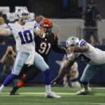 Dallas Cowboys quarterback Cooper Rush (10) tosses the ball as Cincinnati Bengals defensive end Trey Hendrickson (91) closes in during the second half of an NFL football game Sunday, Sept. 18, 2022, in Arlington, Tx. (AP Photo/Ron Jenkins)
