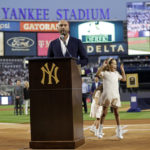 Baseball Hall of Famer Derek Jeter speaks as his daughter Bella Raine jumps by his side during a ceremony honoring his Hall of Fame induction, before a baseball game between the Tampa Bay Rays and the New York Yankees on Friday, Sept. 9, 2022, in New York. (AP Photo/Adam Hunger)
