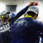 Los Angeles Dodgers manager Dave Roberts, left, celebrates with players in the locker room after the team's 4-0 win in a baseball game against the Arizona Diamondbacks in Phoenix, Tuesday, Sept. 13, 2022. The Dodgers clinched the National League West. (AP Photo/Ross D. Franklin)