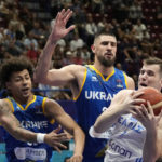 Greece's Dimitrios Agravanis, right, challenges for the ball with Ukraine's Issuf Sanon, left, and Ukraine's Alex Len during their Eurobasket group C basketball match in Milan, Italy, Tuesday, Sept. 6, 2022. (AP Photo/Antonio Calanni)