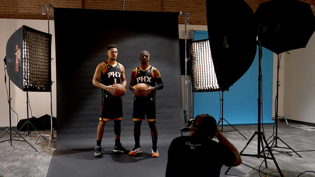 Phoenix Suns' Chris Paul, right, and Devin Booker pose for a photo with team photographer Barry Gos...