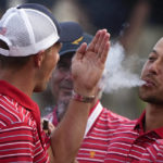 Xander Schauffele blows smoke toward Jordan Spieth after the USA team defeated the International team in a singles match at the Presidents Cup golf tournament at the Quail Hollow Club, Sunday, Sept. 25, 2022, in Charlotte, N.C. (AP Photo/Chris Carlson)