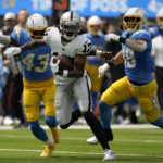 Las Vegas Raiders wide receiver Davante Adams (17) runs in front of Los Angeles Chargers cornerback Michael Davis (43) and linebacker Drue Tranquill during the first half of an NFL football game in Inglewood, Calif., Sunday, Sept. 11, 2022. (AP Photo/Gregory Bull)