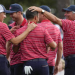 USA team members congratulate Xander Schauffele, center, on the 18th green after Schauffele won the hole and match during their singles match at the Presidents Cup golf tournament at the Quail Hollow Club, Sunday, Sept. 25, 2022, in Charlotte, N.C. Team USA won the Presidents Cup golf tournament. (AP Photo/Chris Carlson)