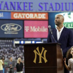 Baseball Hall of Famer Derek Jeter speaks as his daughter Bella Raine smiles by his side during a ceremony honoring his Hall of Fame induction last year, before a baseball game between the Tampa Bay Rays and the New York Yankees on Friday, Sept. 9, 2022, in New York. (AP Photo/Adam Hunger)