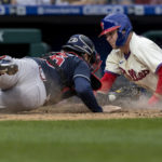 Philadelphia Phillies Rhys Hoskins, right, is safe on a play at home before Atlanta Braves catcher Travis d'Arnaud (16) can make the tag during the fifth inning of a baseball game, Sunday, Sept. 25, 2022, in Philadelphia. (AP Photo/Laurence Kesterson)