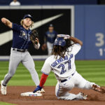 
              Tampa Bay Rays second baseman Taylor Walls, left, throws to first base to complete a double play on Toronto Blue Jays Bo Bichette after forcing Vladimir Guerrero Jr (27) at second base in the first inning of the first baseball game of a doubleheader in Toronto, Tuesday, Sept. 13, 2022. (Jon Blacker/The Canadian Press via AP)
            