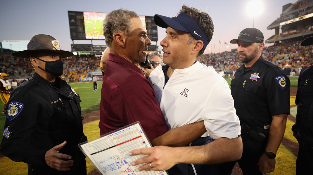 Head coaches Herm Edwards of the Arizona State Sun Devils and Jedd Fisch of the Arizona Wildcats hu...