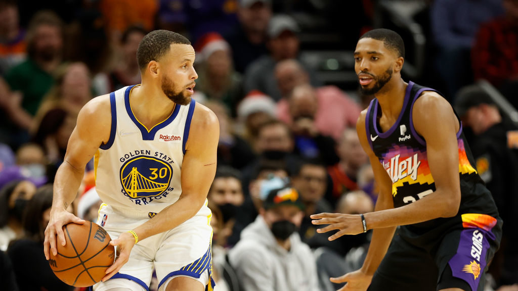 Stephen Curry #30 of the Golden State Warriors looks to pass around Mikal Bridges #25 of the Phoeni...