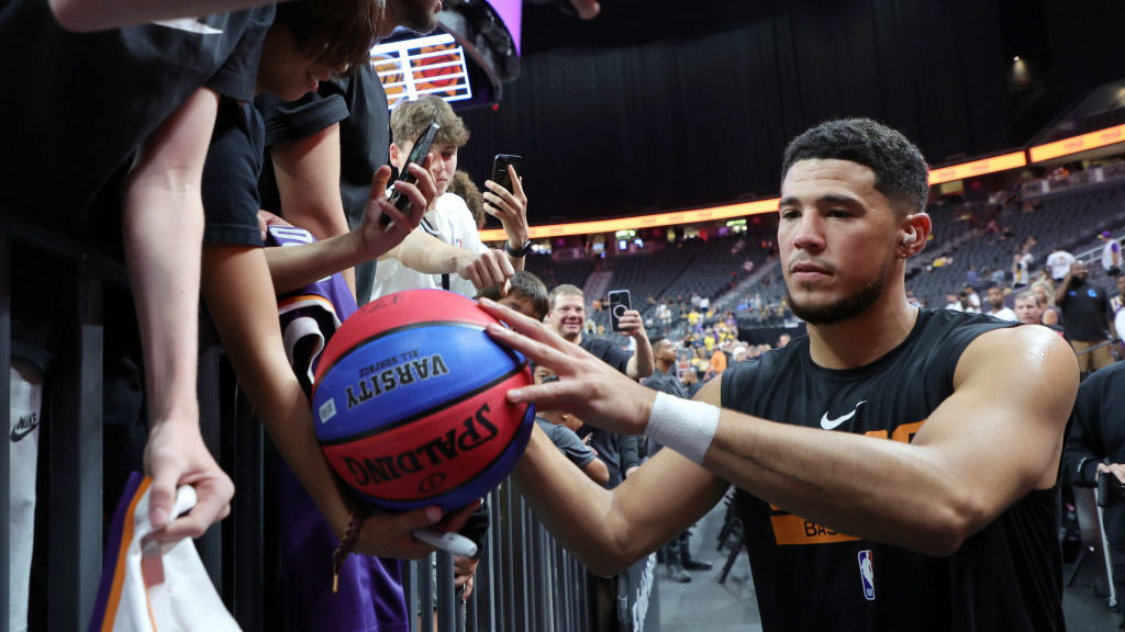Devin Booker #1 of the Phoenix Suns signs autographs for fans before a preseason game against the L...