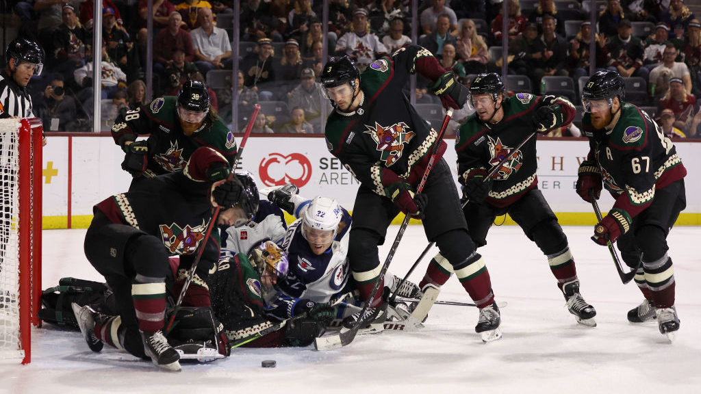 Goaltender Karel Vejmelka #70, Liam O'Brien #38 and Josh Brown #3 of the Arizona Coyotes attempt to...