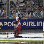 Marshals clear the track of surface water after rain delays the start of the Singapore Formula One Grand Prix, at the Marina Bay City Circuit in Singapore, Sunday, Oct. 2, 2022. (AP Photo/Vincent Thian)