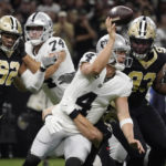 
              Las Vegas Raiders quarterback Derek Carr (4) throws a ball as he is tackled by New Orleans Saints linebacker Kaden Elliss (55) during the first half of an NFL football game Tuesday, Jan. 1, 2019, in New Orleans. (AP Photo/Kiichiro Sato)
            