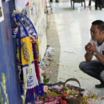 
              A man prays for the victims of Saturday's soccer match stampede in front of gate 13 the Kanjuruhan Stadium in Malang, Indonesia, Tuesday, Oct 4, 2022. A police chief and nine elite officers were removed from their posts Monday and 18 others were being investigated for responsibility in the firing of tear gas inside a soccer stadium that set off a stampede, killing over 100 people, officials said. (AP Photo/Achmad Ibrahim)
            
