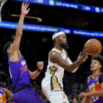 New Orleans Pelicans forward Naji Marshall dishes off as Phoenix Suns guard Devin Booker, left, defends during the first half of an NBA basketball game, Friday, Oct. 28, 2022, in Phoenix. (AP Photo/Matt York)