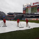 Washington Nationals grounds crew removes water from a tarp before a baseball game between the Philadelphia Phillies and Washington Nationals, Sunday, Oct. 2, 2022, in Washington. (AP Photo/Luis M. Alvarez)