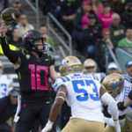Oregon's Bo Nix, left, throws down field ahead UCLA's Darius Muawai during the first half in an NCAA college football game Saturday, Oct. 22, 2022, in Eugene, Ore. (AP Photo/Chris Pietsch)
