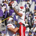 Wisconsin offensive lineman Tanor Bortolini, left, lifts wide receiver Skyler Bell, center, after Bell scored a touchdown against Northwestern during the first half of an NCAA college football game on Saturday, Oct. 8, 2022, in Evanston, Ill. (AP Photo/Kamil Krzaczynski)