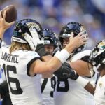 Jacksonville Jaguars quarterback Trevor Lawrence (16) celebrates with his teammates after he ran in for a touchdown during the second half of an NFL football game against the Indianapolis Colts, Sunday, Oct. 16, 2022, in Indianapolis.(AP Photo/Michael Conroy)