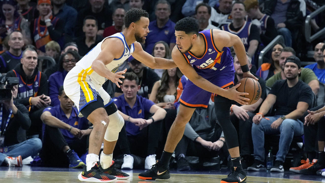 Golden State Warriors guard Stephen Curry and Phoenix Suns guard Devin Booker (1) face off during t...