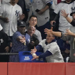 
              Fans reach for a ball hit by New York Yankees Josh Donaldson as it bounces off the top of the wall during the fifth inning of Game 1 of an American League Division baseball series between the New York Yankees and the Cleveland Guardians, Tuesday, Oct. 11, 2022, in New York. (AP Photo/John Minchillo)
            