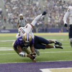 Washington quarterback Michael Penix Jr. dives into the endzone for a touchdown with Arizona cornerback Christian Roland-Wallace defending during the second half of an NCAA football game, Saturday, Oct. 15, 2022, in Seattle. Washington won 49-39. (AP Photo/John Froschauer)